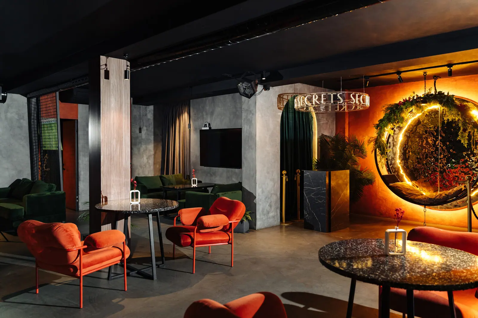 Зал Secrets Lounge: оранжевые кресла, зелёный бархат, бетон, неоновая вывеска и светящийся венок-качели